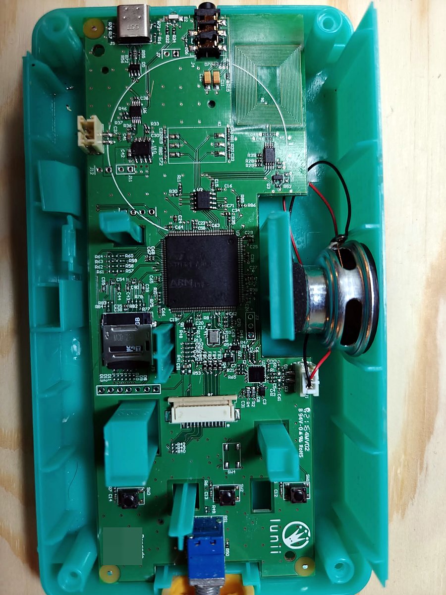 The Lunii V2 with its case open: green board with an ST ARM microcontroller in the middle, the microSD socket at its lower left, USB-C and headphone jack at the top, and the speaker on the right