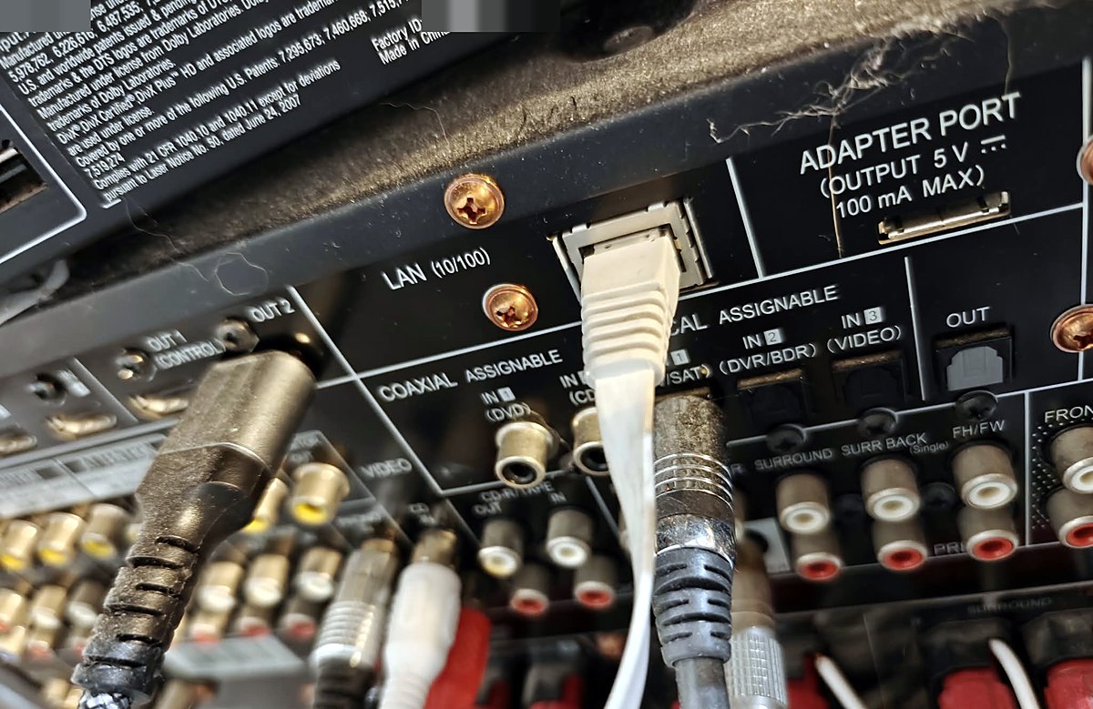 Rear panel of the receiver: a white Ethernet cable plugged into the LAN (10/100) port, between the optical inputs and the adapter port