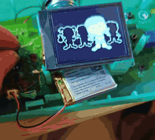 Animated: the opened Lunii box running on the bench, its screen cycling through the character selection